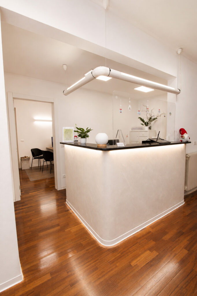 Corridoio dello studio con dispenser di gel disinfettante e il bancone della reception sulla destra