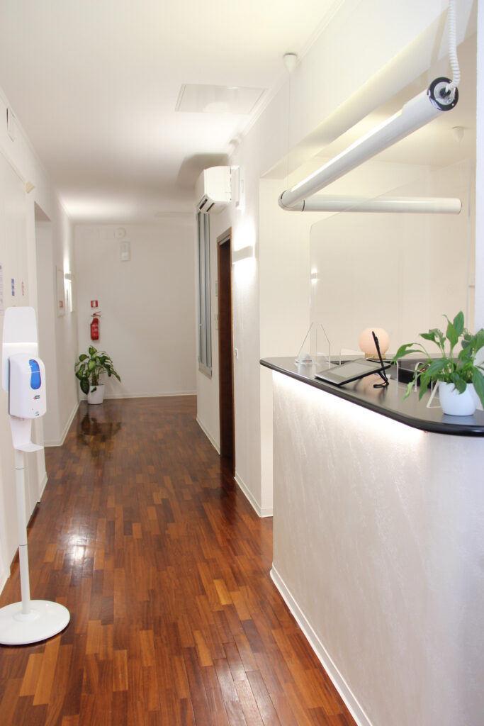 Bancone della reception illuminato, con una pianta e la sala d'attesa sullo sfondo